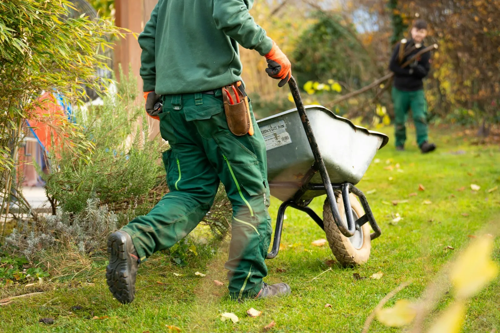 A man pulling a wheelbarrow across a job site.